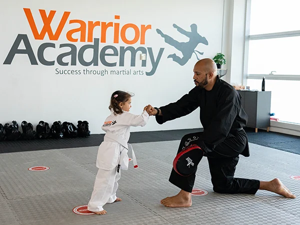 Warrior Academy trainer teaches martial arts to young child.