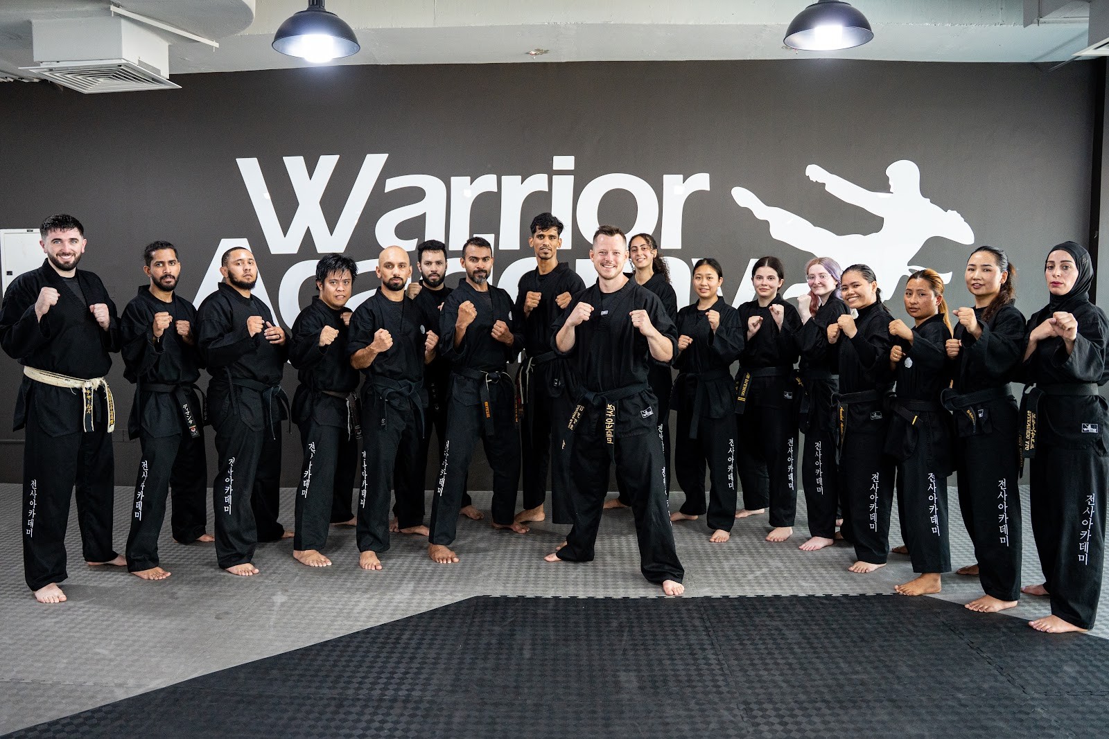 The Warrior Academy instructor team lined up in the dojo in fighting stance