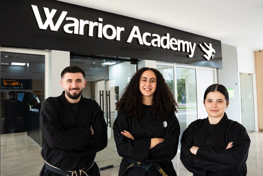 Three members of The Warrior Academy team, arms folded, in front of the academy